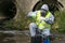 A man in a protective suit and mask from bacteria and viruses pours reagent from a flask into a test tube