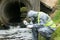 A man in a protective suit takes a sample of water from the river after the release of chemical waste