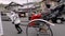 A man-pulled rickshaw transports two passengers in the Arashiyama district of Kyoto, Japan