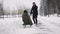 Man pulling girl on a sled at snow