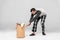 Man pulling heavy laundry basket with dirty clothing on grey