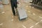 Man pulling his trolley baggage behind him at airport, view from back, only legs and luggage on floor visible