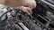 A man pulls out an old spark plug from a car engine