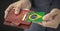 Man pulls plastic card with flag of Brazil out of his wallet, fictional card number