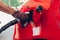 Man pumping gas fuel into car tank at filling station. Petrol station worker holds nozzle refueling automobile.