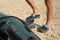 Man pumping inflatable rubber fishing boat at sandy beach on sunny day, closeup