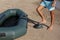 Man pumping inflatable rubber fishing boat at sandy beach on sunny day, closeup