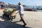 A man pushing a cart loaded with baskets full of goods in the port of the Chinese fishing water village.