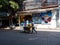 Man pushing his cooking cart past a local pastry shop on N Sathon Road by Saphan Taksin in Bangkok, Thailand