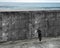 Man pushing huge puzzle door of concrete wall