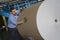 Man Pushing Huge Roll Of Paper In Factory