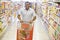 Man pushing trolley along supermarket aisle