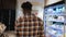 Man pushing trolley along supermarket at store, rear view