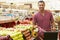 Man Pushing Trolley By Fruit Counter In Supermarket