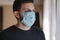 Man put on madical mask at home. Young man in protective mask. Coronavirus theme