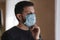 Man put on madical mask at home. Young man in protective mask. Coronavirus theme