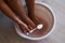 Man put spoon of baking soda in bath with hot water for his feet. Homemade bath soak for dry feet skin