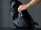 A man puts alcohol gel in a black modern backpack.