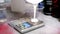 Man puts empty cup onto digital scale and pours white paint