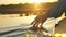 man puts fingers down lake kayaking against backdrop of golden sunset, unity harmony nature
