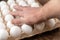 A man puts his hand on top of a cardboard tray of chicken eggs. Open recycled tray