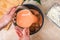 A man puts lazy cabbage rolls into multicooker bowl and pours tomato and sour cream sauce over them.