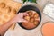 A man puts lazy cabbage rolls into multicooker bowl and pours tomato and sour cream sauce over them.