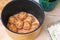 A man puts lazy cabbage rolls into multicooker bowl and pours tomato and sour cream sauce over them.