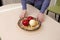 Man puts plate with artificial fruit on a glossy dining table