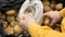 A man puts potatoes in plastic bag in a supermarket close-up.