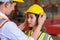 Man puts a safety helmet on woman at factory or plant site. Business heir concept. Happy lover wearing safety helmet on together