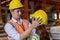 Man puts a safety helmet on woman at factory or plant site. Business heir concept. Happy lover wearing safety helmet on together