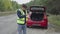 A man puts on a vest when a car breaks down on the road.