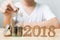 Man putting coin in jar with wood number 2018 year, Save money a