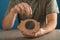 Man putting coin into piggy bank at table, closeup. Money savings concept