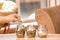 Man putting coins into glass jars on table. Savings concept