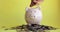 Man putting coins in piggy bank standing in pile of coins, hand closeup.