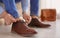 Man putting on elegant leather shoes indoors,