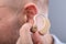 Man Putting Hearing Aid In His Ear