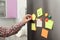 Man putting paper sheet on refrigerator door at home