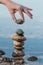 Man putting pebble on stone balance in the water of lake with reflection