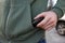 Man putting pepper spray into sweater pocket outdoors, closeup