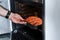 Man putting raw salmon steak into oven