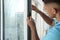 Man putting rubber draught strip onto window indoors, focus on hands