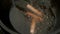 Man is putting sausages in boiling oil to frying in cauldron, closeup view.