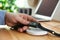 Man putting smartwatch onto wireless charger at table, closeup. Modern workplace accessory