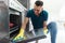 Man with rag cleaning oven door at home kitchen