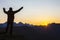 Man with raised hands standing on the mountain face to sunrise. Tourist traveler in the mountains meets a sunny dawn