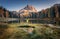 Man with raised up arms on Antorno lake in autumn at sunrise