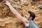 Man reaching for a grip while he rock climbs